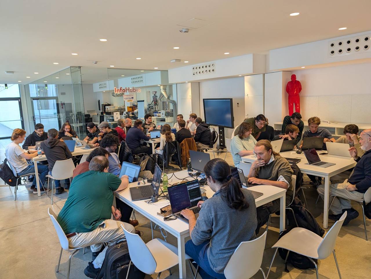 A photo of one of the first Zig Days organized in Milan showing people sitting around a few tables with their laptops open, chatting while programming.
